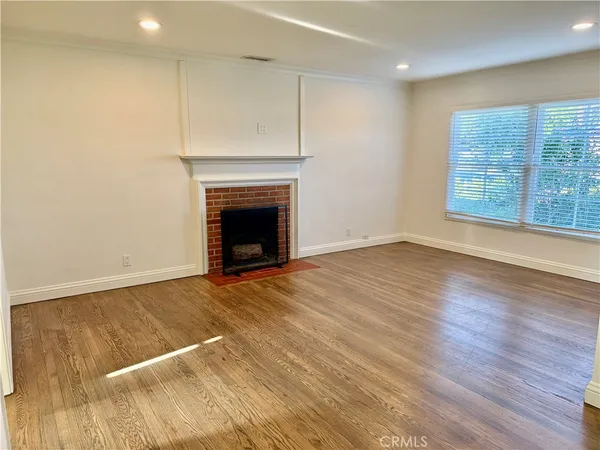 a view of empty room with wooden floor and fireplace