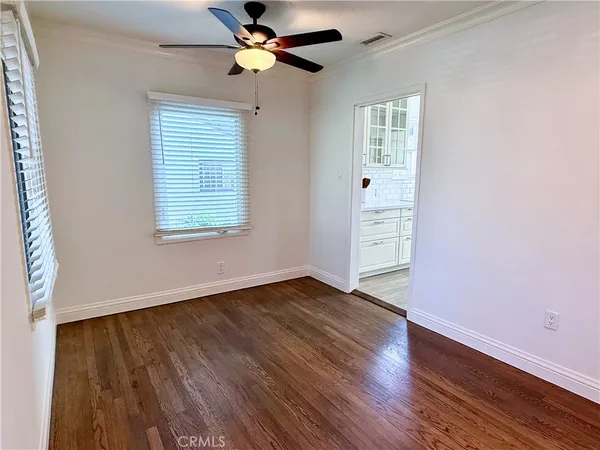 an empty room with wooden floor chandelier fan and windows