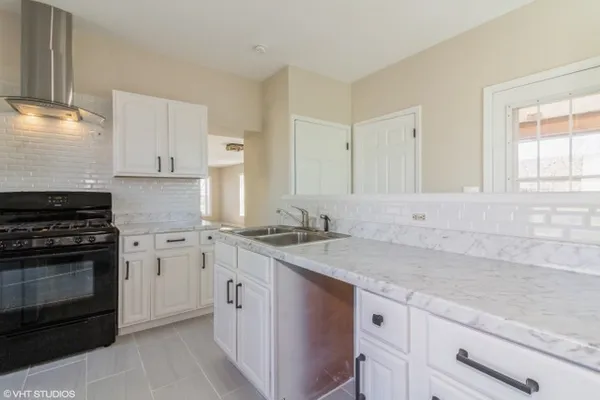 a kitchen with granite countertop a sink stove and cabinets