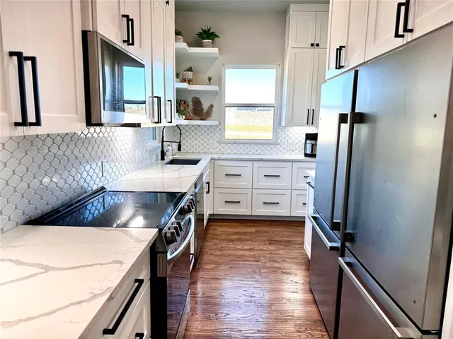 a kitchen with stainless steel appliances cabinets a sink and a refrigerator