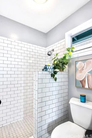 a bathroom with a toilet a sink a mirror and shower