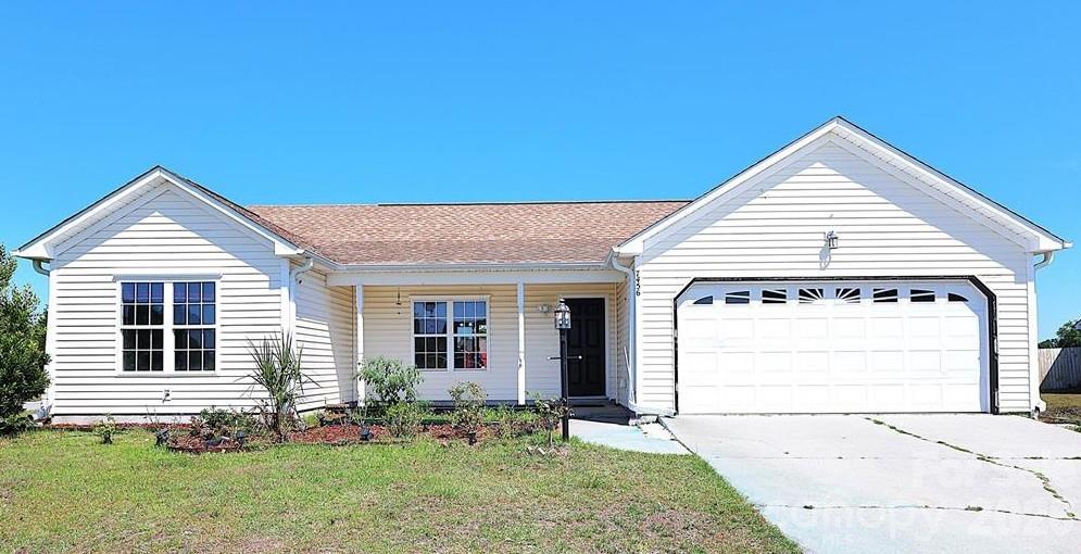 7456 Courtney Pines Road Wilmington, NC 28411 - Photo 12 of 16 a view of a house with a small yard and plants