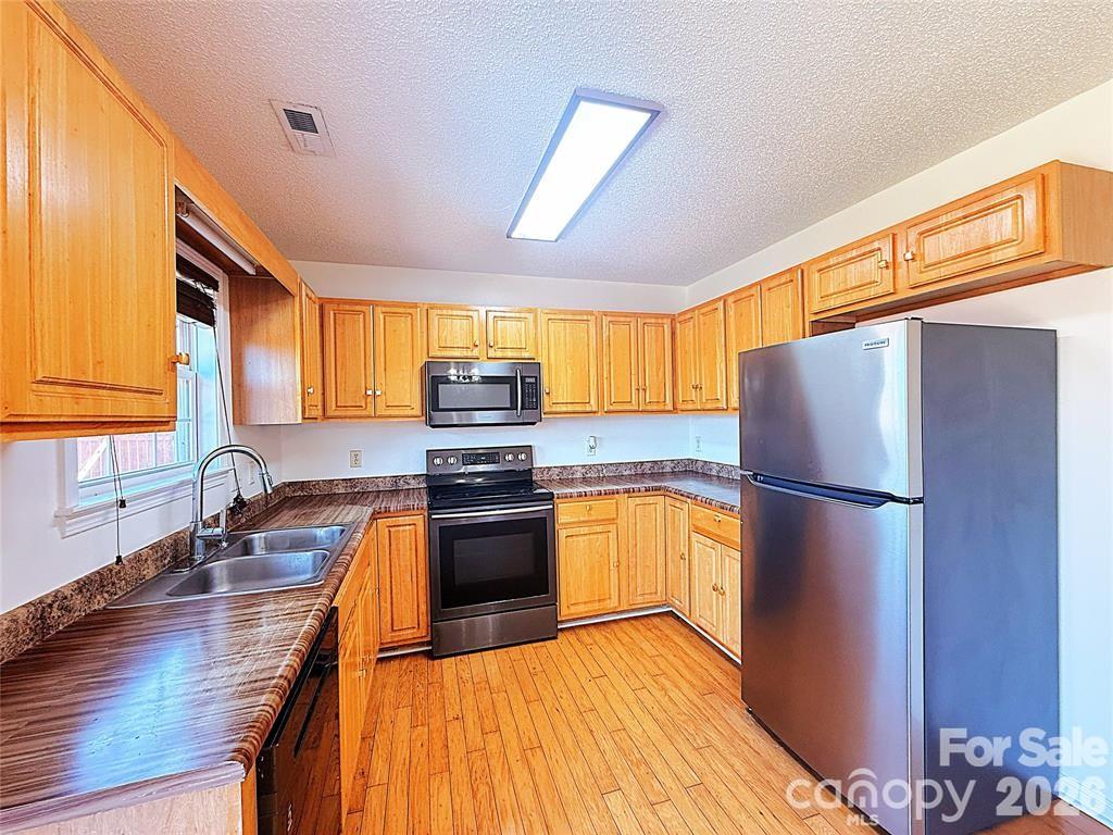 7456 Courtney Pines Road Wilmington, NC 28411 - Photo 4 of 16 a kitchen with stainless steel appliances granite countertop a refrigerator sink stove microwave and cabinets