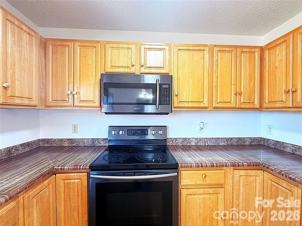 7456 Courtney Pines Road Wilmington, NC 28411 - Photo 5 of 16 a kitchen with stainless steel appliances granite countertop a stove and a microwave