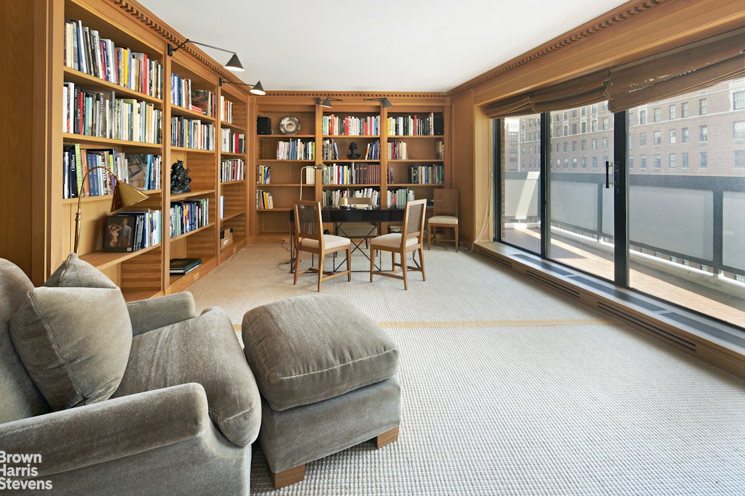 a living room with furniture a bookshelf and a large window