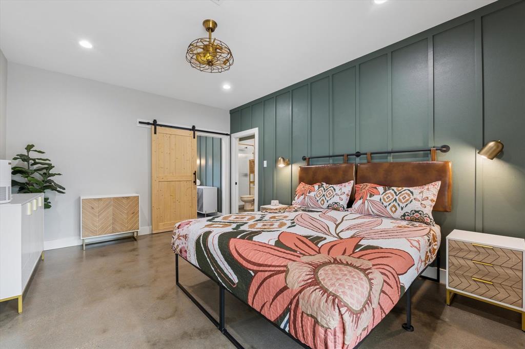 286 Benevolence Way China Spring, TX 76633 - Photo 13 of 37 Modern bedroom featuring a paneled accent wall, concrete flooring, a natural wood barn door, and recessed lighting