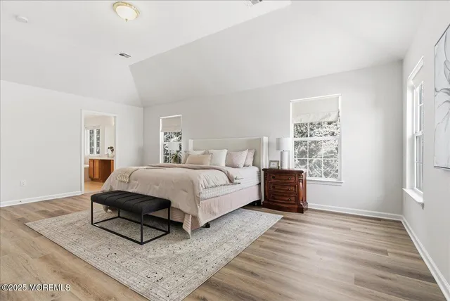 a spacious bedroom with a bed and wooden floor
