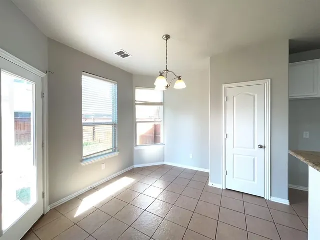 a view of an empty room with window and chandelier fan