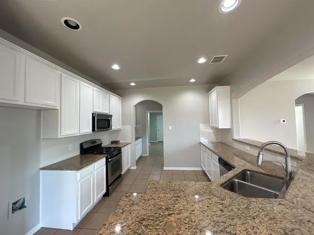 a open kitchen with stainless steel appliances granite countertop a sink a stove and cabinets