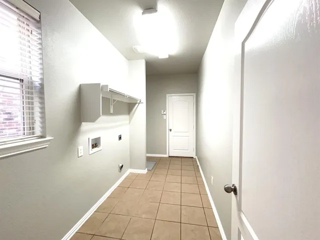 a view of a hallway with wooden floor and a bathroom