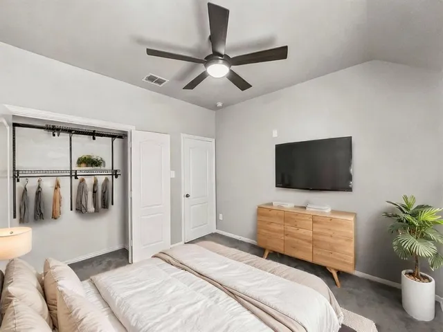 a bedroom with a bed a flat screen tv and a couch