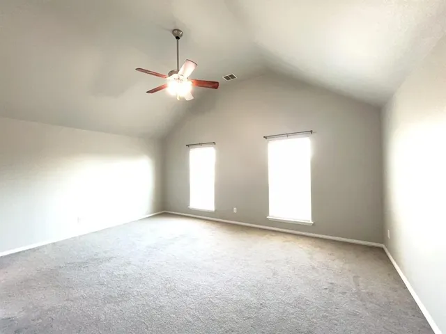 a view of a big room with windows and chandelier fan