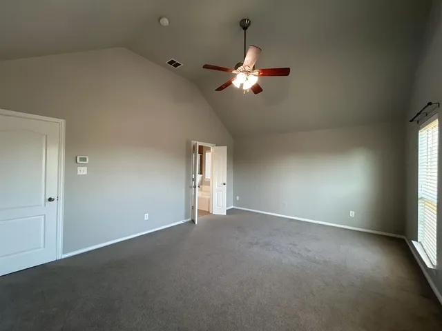 an empty room with windows and fan
