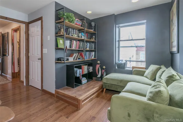 a living room with furniture a bookshelf and a window