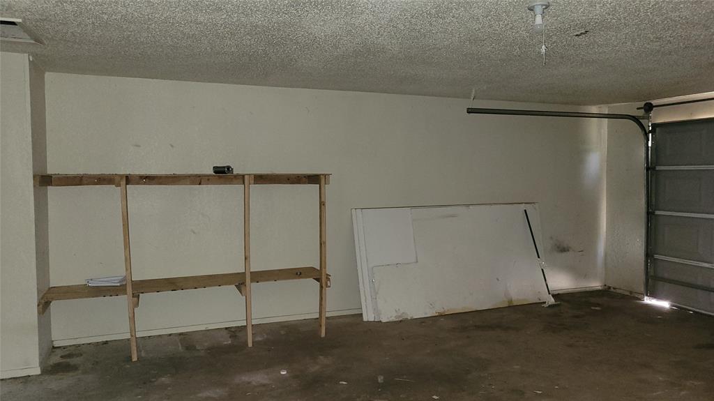 902 South Old Temple Road Hewitt, TX 76643 - Photo 27 of 32 Utility garage featuring a textured ceiling, concrete flooring, and built-in wooden shelving for storage