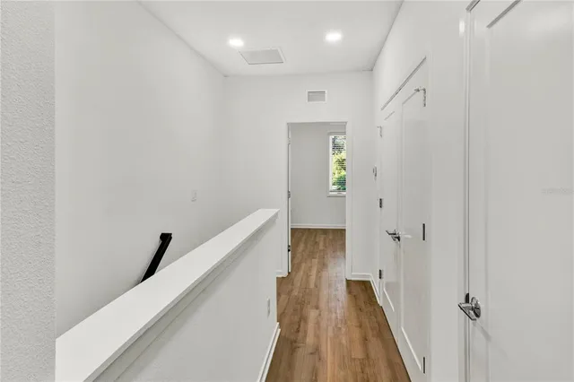 a view of a hallway with wooden floor and staircase