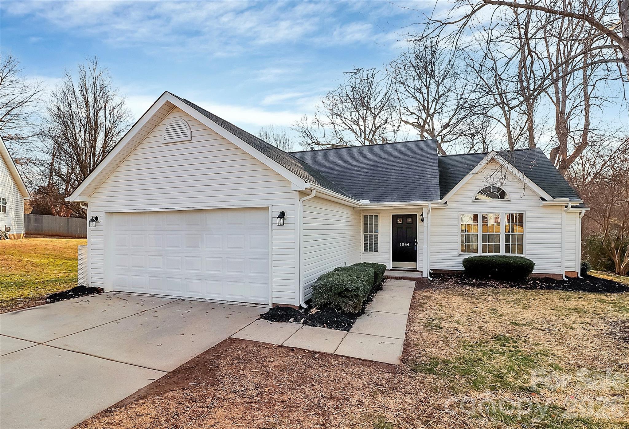 1044 Sandy Point Drive Southwest Concord, NC 28025 - Photo 1 of 32 a view of a white house with a yard and large trees