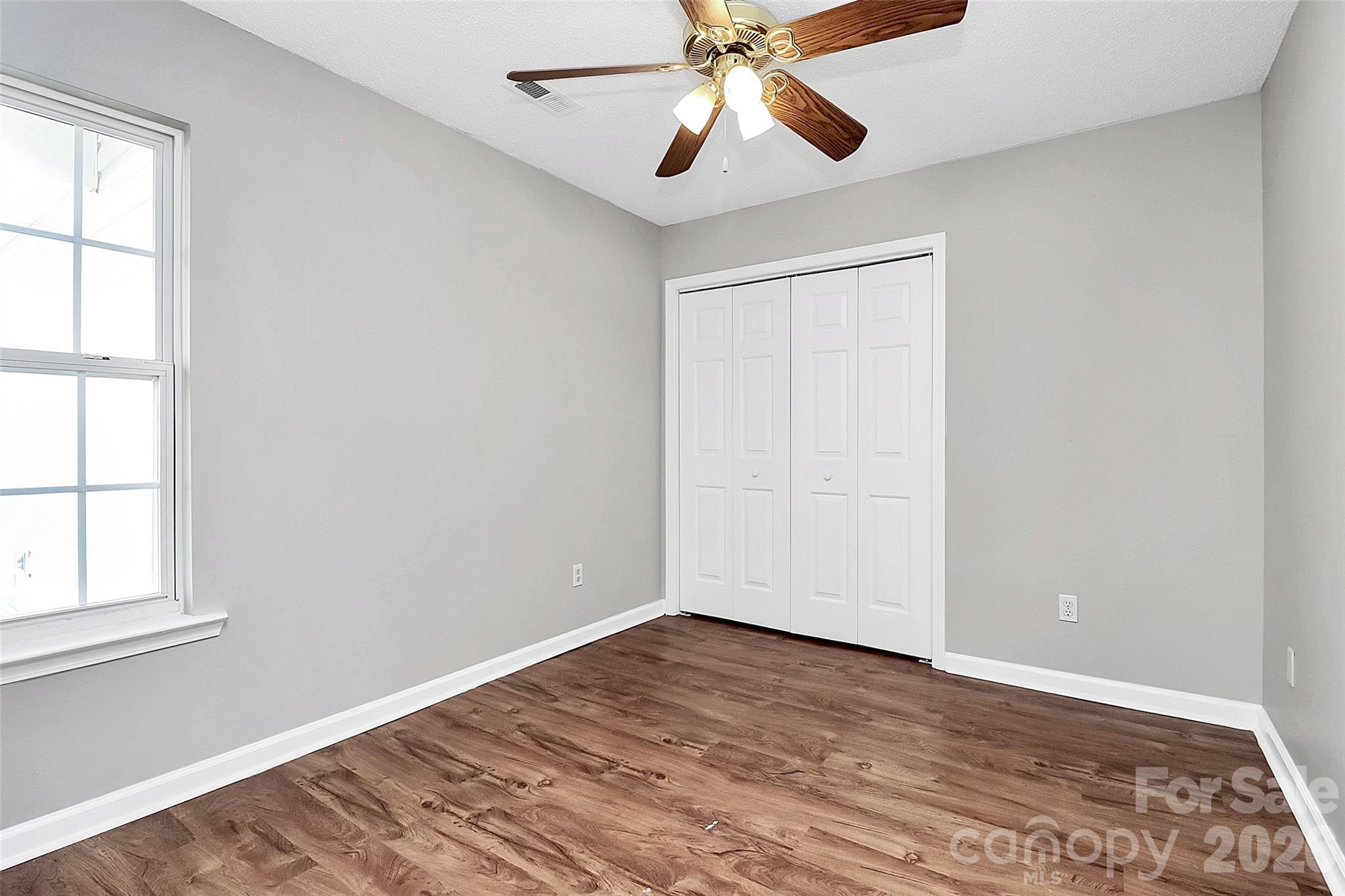 1044 Sandy Point Drive Southwest Concord, NC 28025 - Photo 23 of 32 an empty room with wooden floor chandelier fan and windows