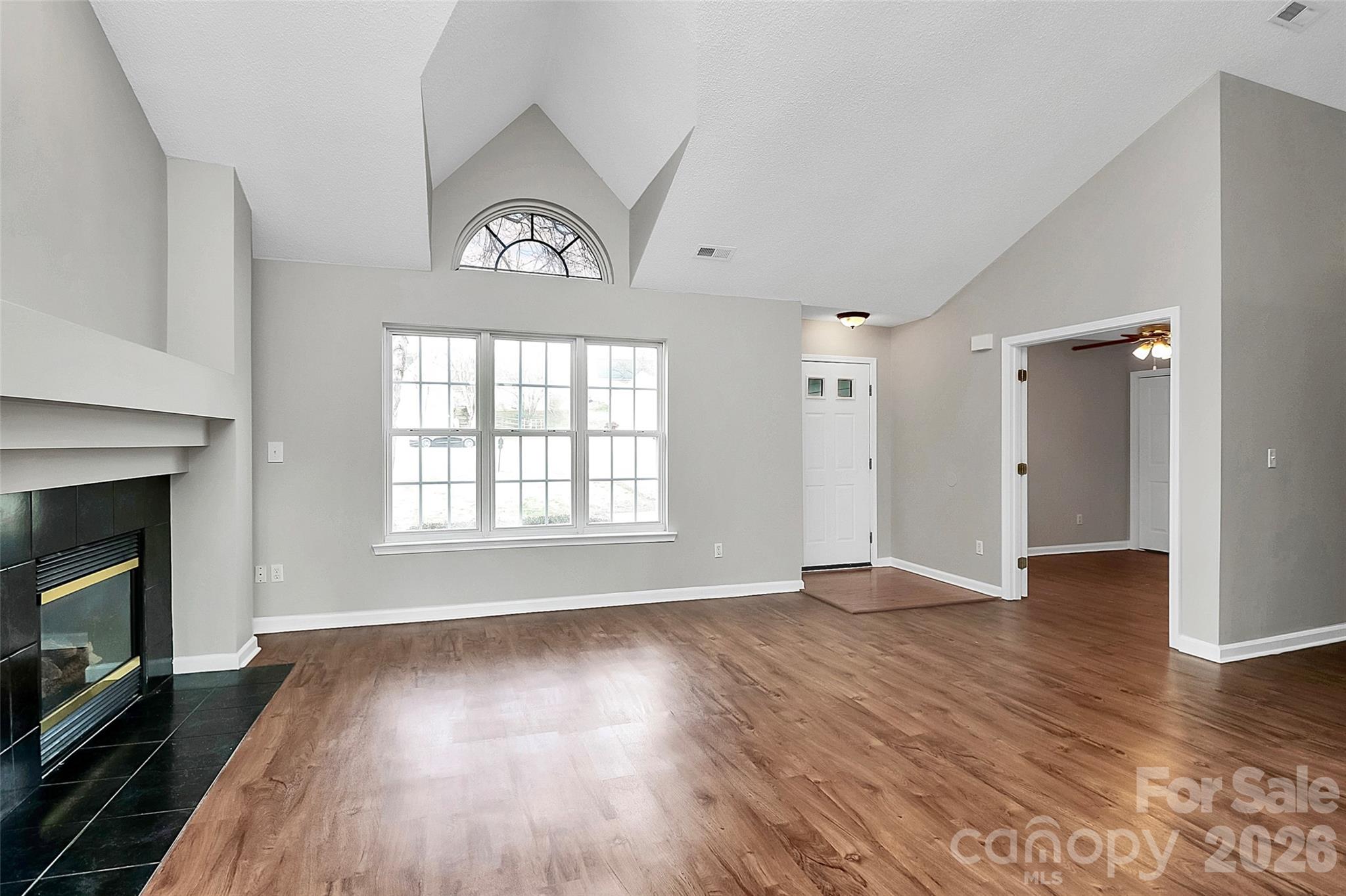 1044 Sandy Point Drive Southwest Concord, NC 28025 - Photo 5 of 32 an empty room with wooden floor a fireplace and windows