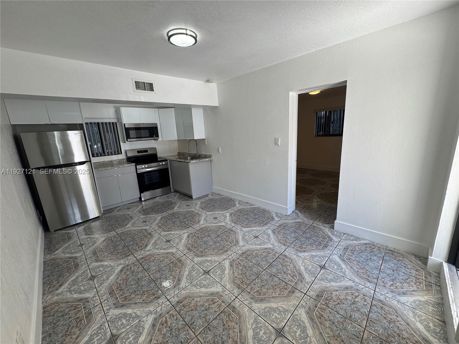 169 Northeast 50th Street, Unit 2 Miami, FL 33137 - Photo 2 of 16 a kitchen with stainless steel appliances granite countertop a refrigerator and a sink