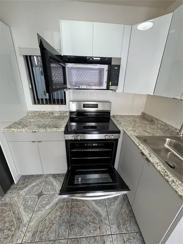 a kitchen with granite countertop a stove and a sink