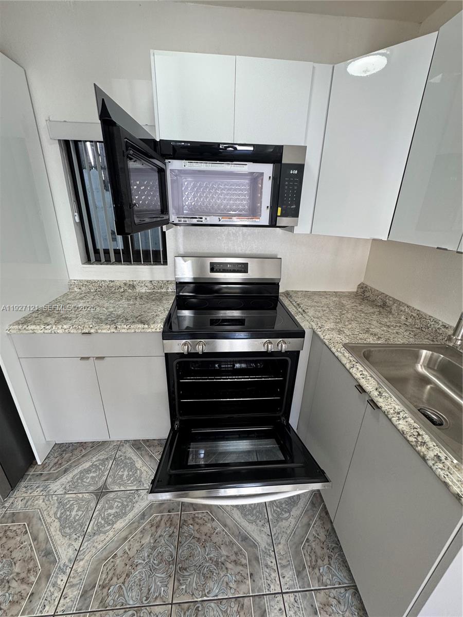 169 Northeast 50th Street, Unit 2 Miami, FL 33137 - Photo 5 of 16 a kitchen with granite countertop a stove and a sink