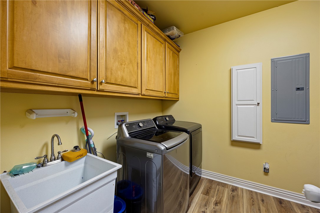 751 Walthall Road Russellville, AR 72802 - Photo 23 of 60 Dedicated laundry space featuring wood-finish flooring, a utility sink with a chrome faucet, and ample overhead wood cabinetry