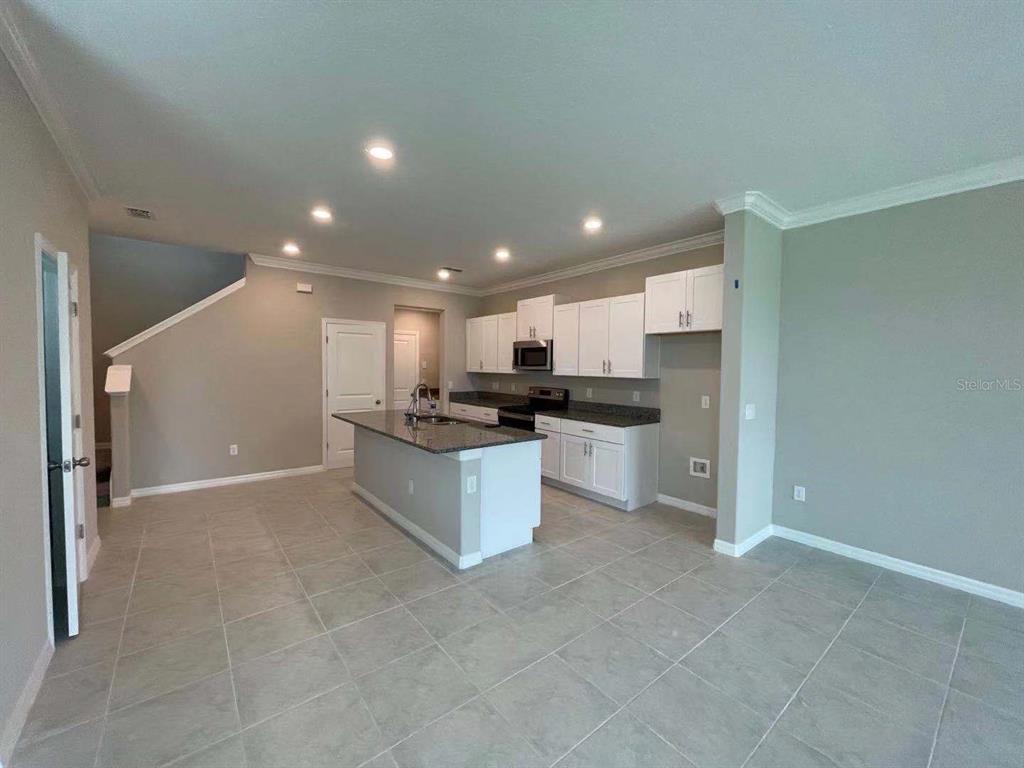 31993 Blue Passing Loop Wesley Chapel, FL 33545 - Photo 3 of 17 a large kitchen with kitchen island a sink a stove a refrigerator and cabinets