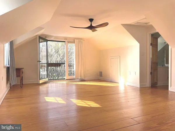 a view of an empty room with window and wooden floor