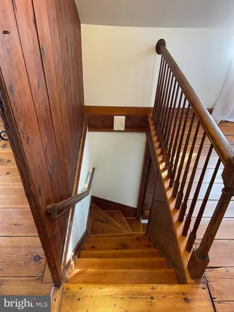 a bedroom with a bed and a dresser with wooden floor