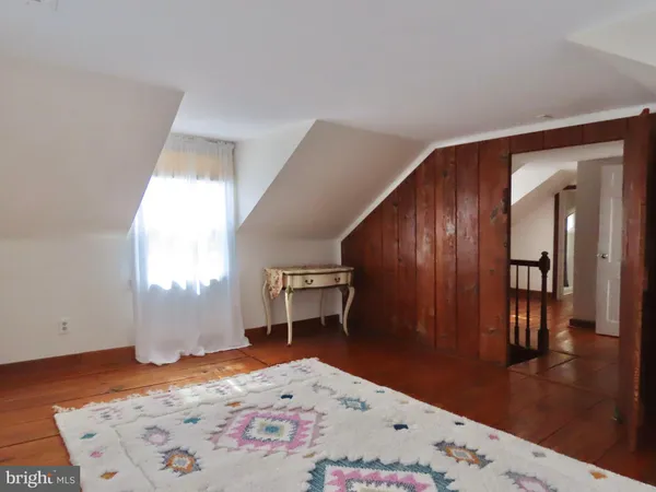 a view of a bedroom with a bed and wooden floor