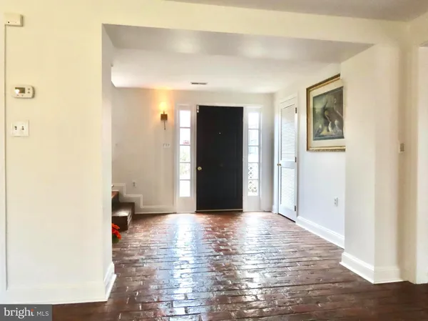 a view of a hallway with wooden floor and a bathroom