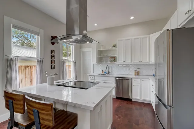 a kitchen with a sink stainless steel appliances cabinets and a window