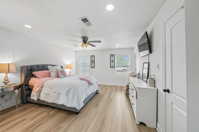 a spacious bedroom with a bed and a flat screen tv