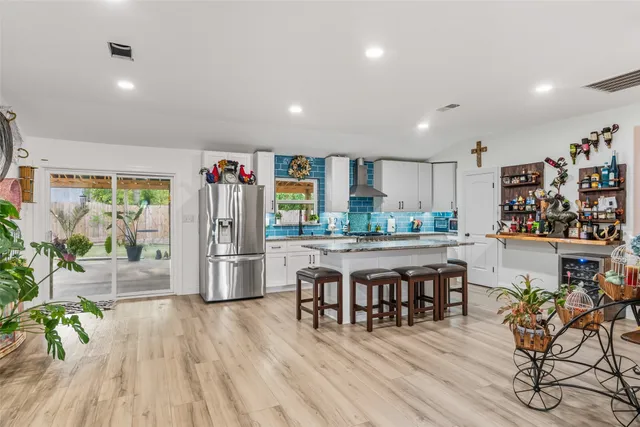 a kitchen with stainless steel appliances granite countertop a refrigerator a microwave oven a dining table and chairs with wooden floor