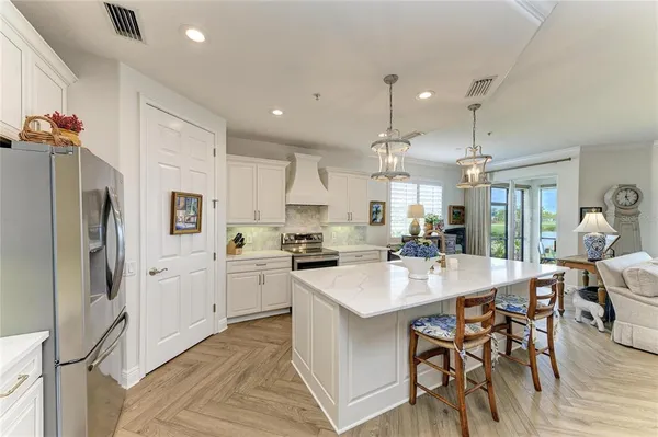 a kitchen with stainless steel appliances a table chairs refrigerator and sink