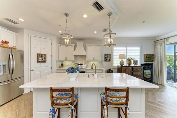 a large white kitchen with lots of counter space a sink appliances and cabinets
