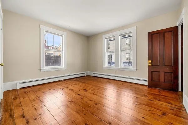 a view of an empty room with window and wooden floor