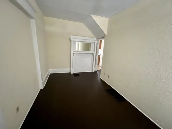an empty room with wooden floor cabinet and a window