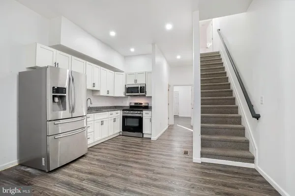 a kitchen with white cabinets stainless steel appliances and wooden floor