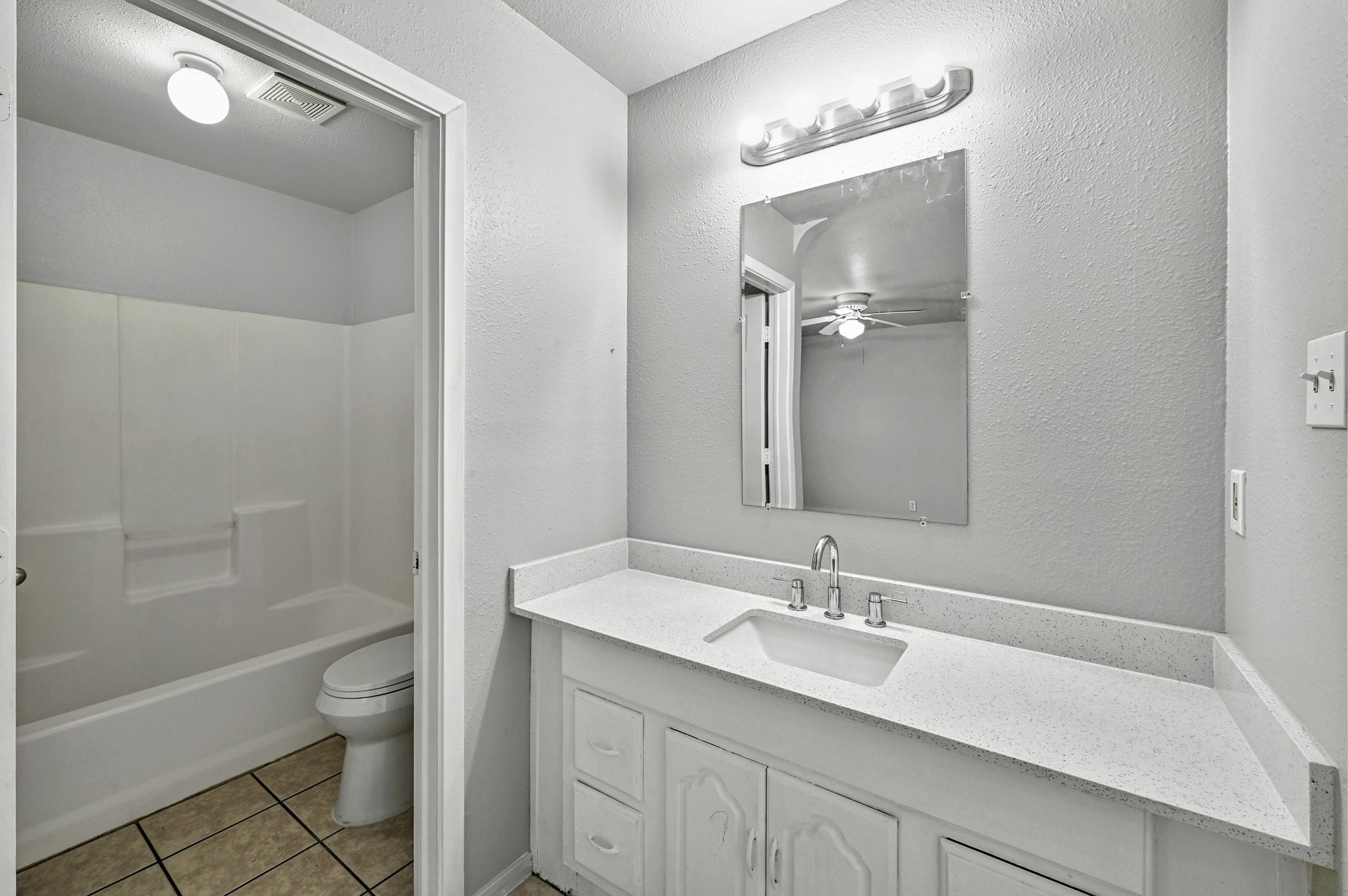 2212 Katy Lane Georgetown, TX 78626 - Photo 20 of 27 The bathroom features a white vanity with a light-colored countertop and an integrated sink, a wall-mounted mirror, and a shower-tub combination with a white surround and a toilet
