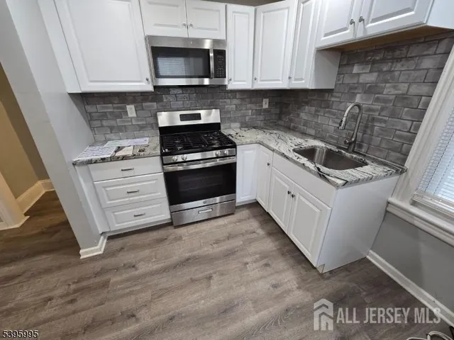 a kitchen with stainless steel appliances white cabinets and a stove top oven