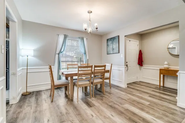 a dining room with wooden floor a chandelier a wooden table and chairs