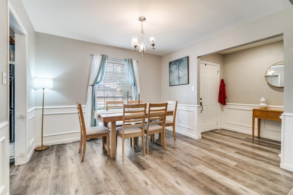 7214 Ridgeview Drive Rowlett, TX 75089 - Photo 3 of 23 a dining room with wooden floor a chandelier a wooden table and chairs