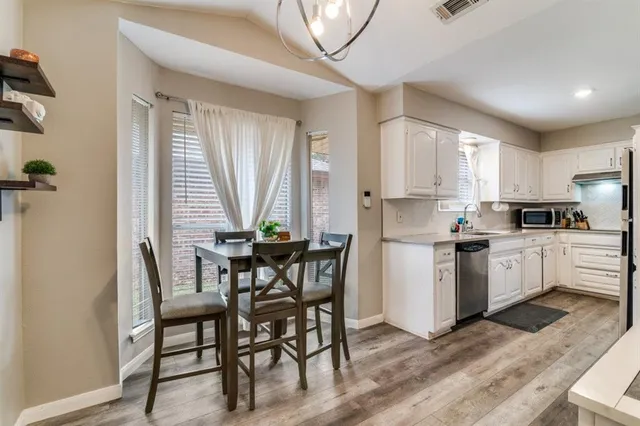 a kitchen with a table chairs a sink a window and stainless steel appliances