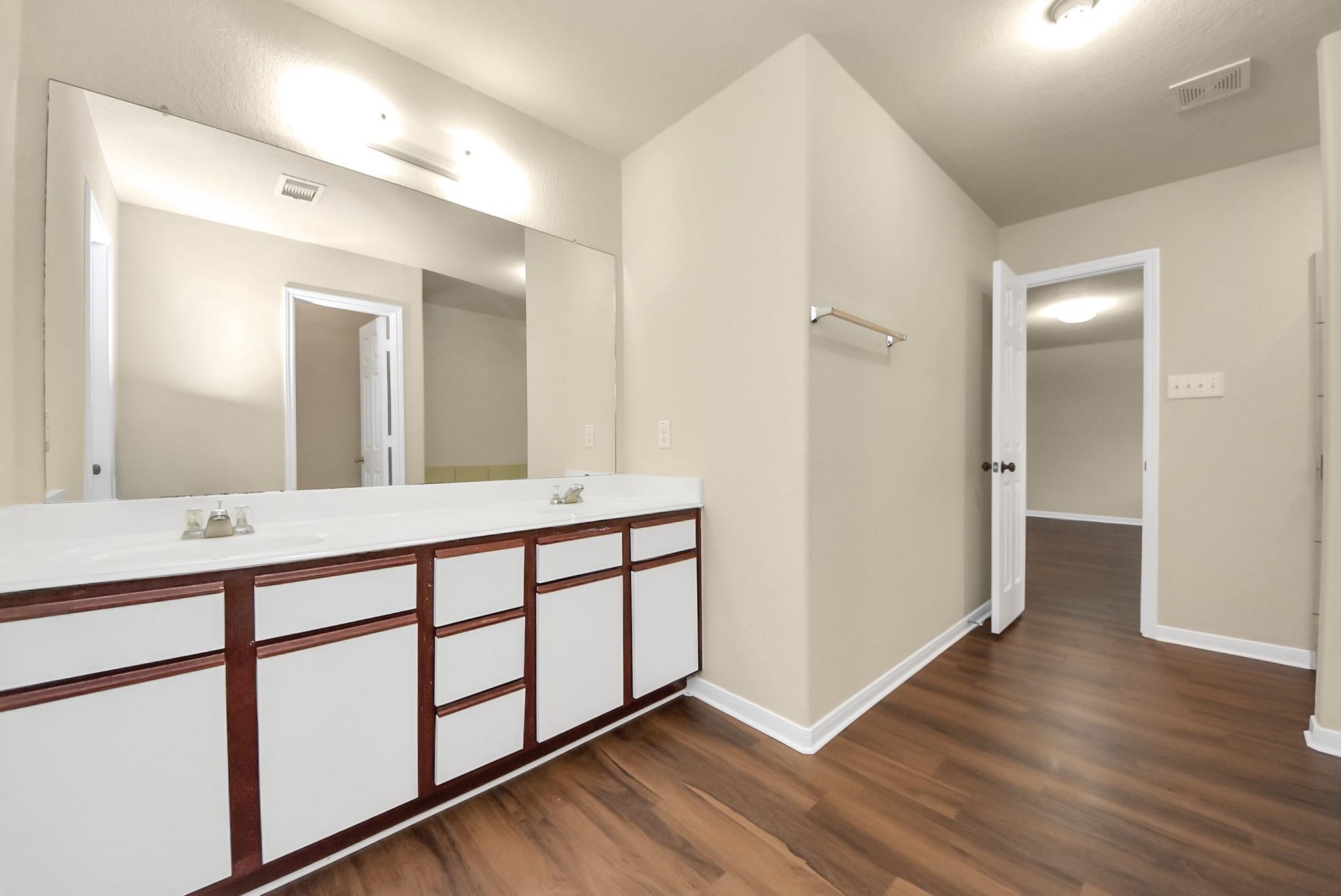 11014 Cape Rise Trail Houston, TX 77044 - Photo 15 of 43 An extended vanity, ample counter space, a large mirror, and warm wood-style flooring; blending practicality with everyday comfort.