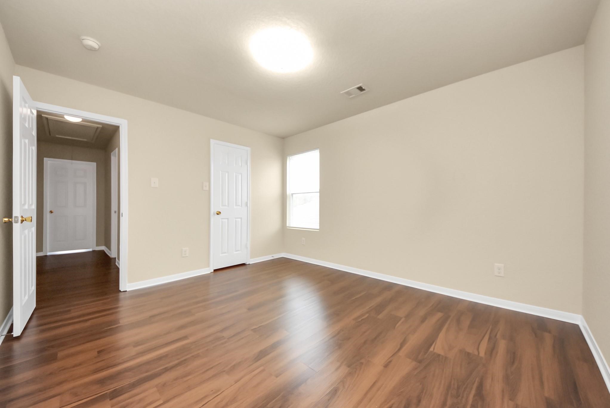 11014 Cape Rise Trail Houston, TX 77044 - Photo 25 of 43 Generously sized bedroom offering beautiful wood-style flooring, soft neutral walls, and abundant natural light, providing a comfortable and versatile retreat.
