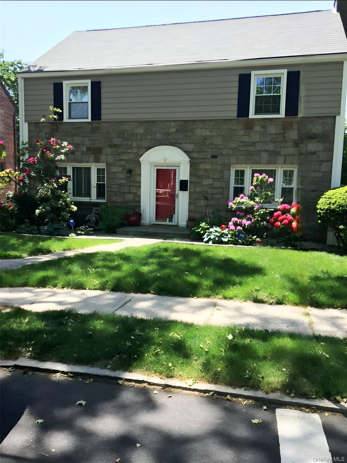 View of front of house with stone siding and a front yard