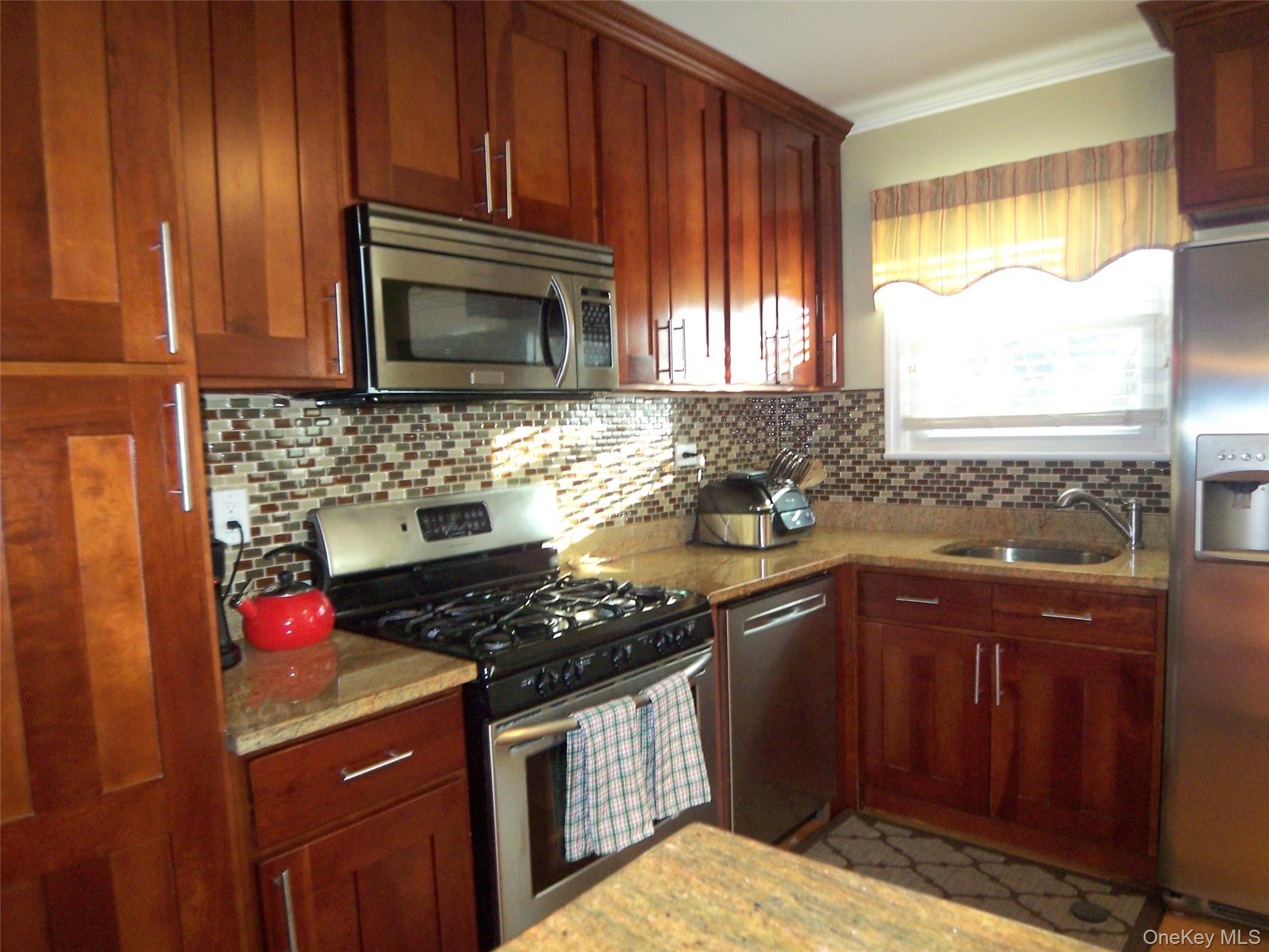 40 Harding Parkway Mount Vernon, NY 10552 - Photo 2 of 35 Kitchen with stainless steel appliances, light stone countertops, decorative backsplash, and bold wood finish cabinets