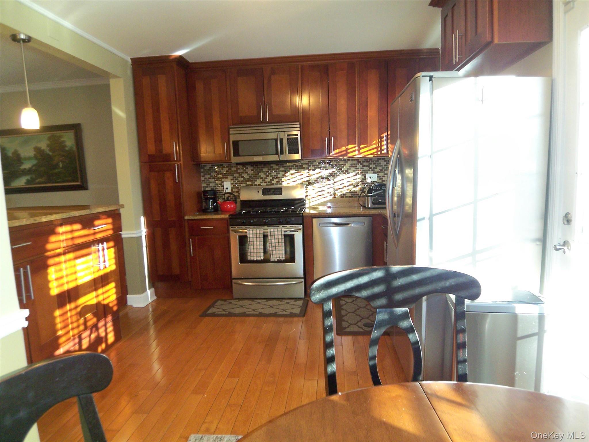40 Harding Parkway Mount Vernon, NY 10552 - Photo 4 of 35 Kitchen with stainless steel appliances, hanging light fixtures, light wood-style flooring, crown molding, and backsplash